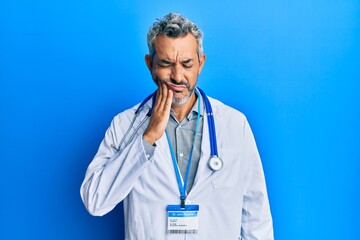 Sticker - Middle age grey-haired man wearing doctor uniform and stethoscope touching mouth with hand with painful expression because of toothache or dental illness on teeth. dentist