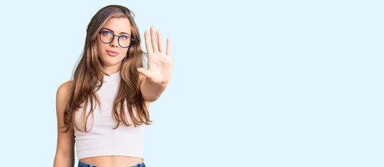 Beautiful caucasian young woman wearing casual clothes and glasses doing stop sing with palm of the hand. warning expression with negative and serious gesture on the face.