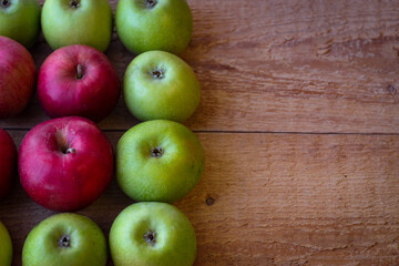 Wall Mural - Green and red apples stand on a wooden surface