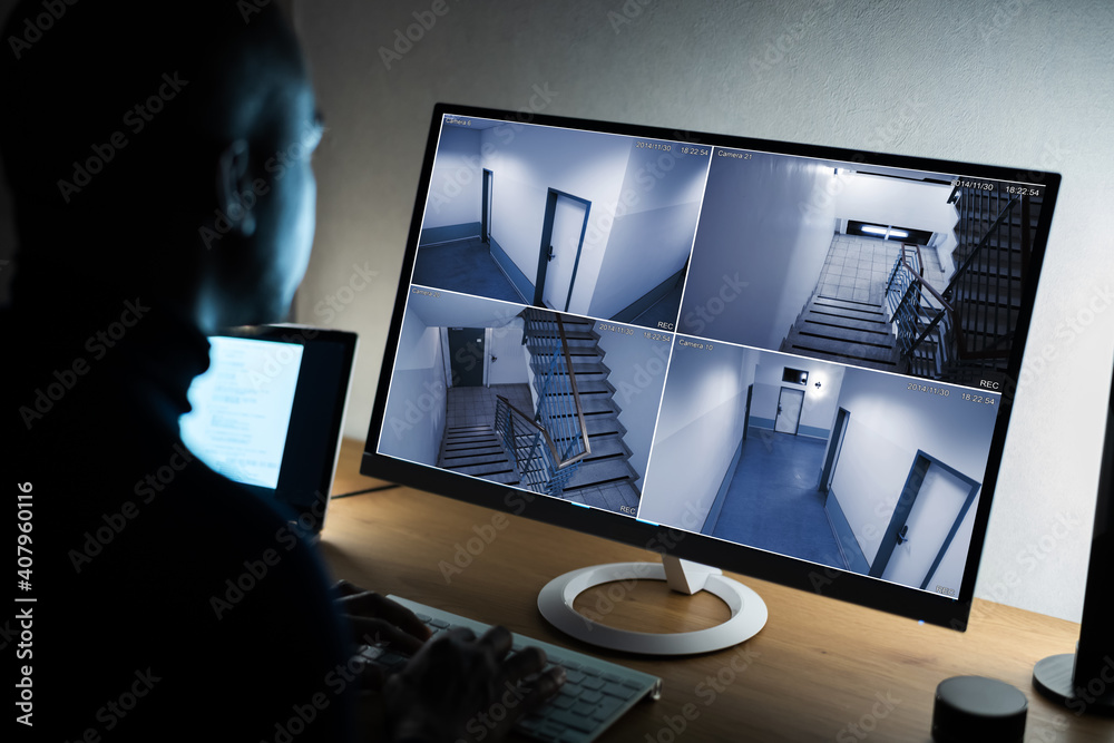 Businessman Watching CCTV Footage Of Office Interior On Computer - obrazy, fototapety, plakaty 