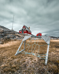 Sticker - Vertical shot of wooden red houses on the top of the rock - Ghost village in Greenland, Assaqutaq