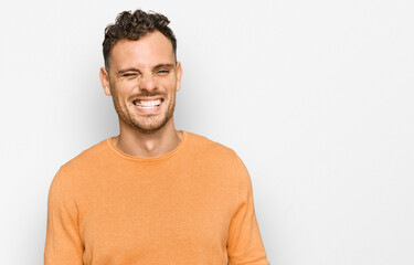 Sticker - Young hispanic man wearing casual clothes winking looking at the camera with sexy expression, cheerful and happy face.