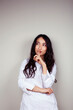 © iordani - young asian woman doctor in white uniform gesturing positive on gray background, lifestyle healthcare people concept