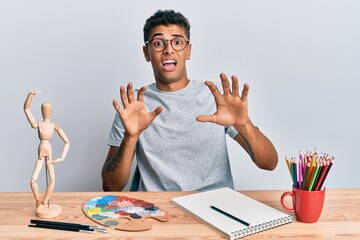 Sticker - Young handsome african american man painter sitting palette and art manikin afraid and terrified with fear expression stop gesture with hands, shouting in shock. panic concept.