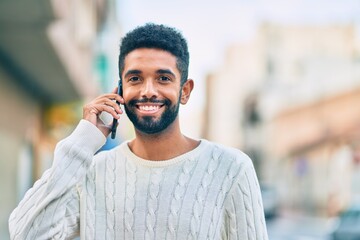 Poster - Young african american man smiling happy talking on the smartphone at the city.