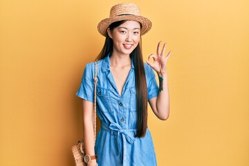 Sticker - Young chinese woman wearing summer hat smiling positive doing ok sign with hand and fingers. successful expression.