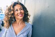 © Krakenimages.com - Middle age hispanic woman smiling happy leaning on the wall at the city.