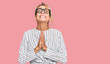 Beautiful blonde woman wearing business shirt and glasses begging and praying with hands together with hope expression on face very emotional and worried. begging.