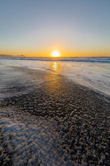 Wall Mural - an amazing sunset over the water at topocalma wild beach. the waves splashing water and the tide goi