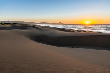 Wall Mural - an amazing sea view during sunset time of an awe sandy beach full of sand dunes till the infinite. i