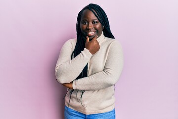 Poster - Young black woman with braids wearing casual winter sweater looking confident at the camera smiling with crossed arms and hand raised on chin. thinking positive.