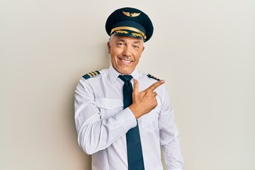 Poster - Handsome middle age mature man wearing airplane pilot uniform cheerful with a smile on face pointing with hand and finger up to the side with happy and natural expression