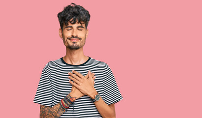 Sticker - Young hispanic man wearing casual clothes smiling with hands on chest with closed eyes and grateful gesture on face. health concept.