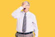 © Krakenimages.com - Senior grey-haired man wearing business clothes peeking in shock covering face and eyes with hand, looking through fingers with embarrassed expression.