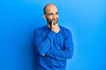 Wall Mural - Young hispanic man wearing casual winter sweater thinking concentrated about doubt with finger on chin and looking up wondering