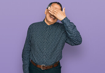 Canvas Print - Middle age indian man wearing casual clothes and glasses smiling and laughing with hand on face covering eyes for surprise. blind concept.