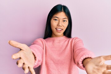 Sticker - Young chinese woman wearing casual clothes looking at the camera smiling with open arms for hug. cheerful expression embracing happiness.