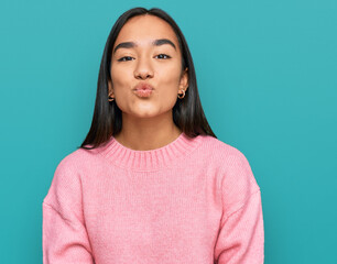 Poster - Young asian woman wearing casual winter sweater looking at the camera blowing a kiss on air being lovely and sexy. love expression.