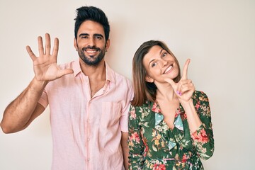 Beautiful young couple of boyfriend and girlfriend together showing and pointing up with fingers number seven while smiling confident and happy.