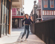 © Touchr - Happy young asian woman listening to music and having fun with headphones on the street.