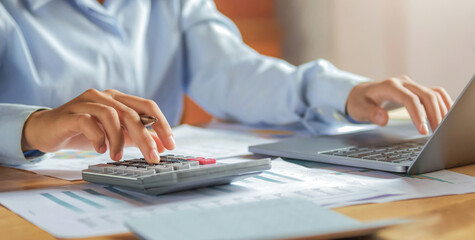 Poster - Woman accountant use calculator and computer with holding pen on desk in office. finance and accounting concept