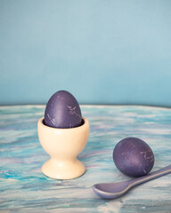 Wall Mural - Painted purple eggs on a stand on a blue background