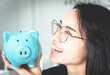 © phoomrat - Business woman  is holding piggy bank in hand, girl saving money in happy face saving money for invest for business and financial concept copy-space white background