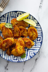 Wall Mural - Fried caramelized plantains served with lime wedges and cilantro overhead shot