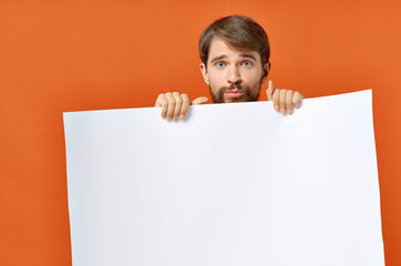 bearded man with poster in hand on orange background Copy Space