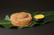 Puran Poli, also known as Holige, is an Indian sweet flatbread from India consumed mostly during Holi festival. Served on banana leaf with pure Ghee over black background.