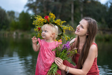 young mother and daughter in wreath of flowers on the lake. ivan kupala holiday