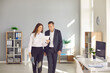 © Studio Romantic - Smiling friendly business woman showing documents to her colleague during a meeting in the office. Man and woman go together in the office and discuss new strategies and business development plans.