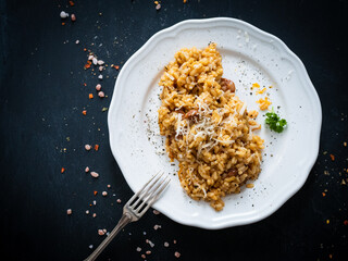 Wall Mural - Risotto with chorizo and parmesan on wooden background

