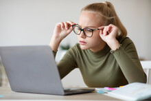 Teen Girl Fixing Her Glasses While Looking At Laptop Screen