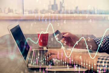 Double exposure of man hands holding a credit card and Forex graph drawing. Stock trading and digital fintech in Internet E-commerce concept.