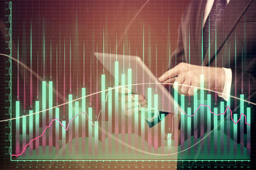 Double exposure of man's hands holding and using a digital device and forex graph drawing. Financial market concept.