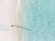 Leinwandbild Motiv Young woman sitting and relaxing at beautiful tropical white sand beach with wave foam and transparent sea, Summer vacation and Travel background Top view from drone