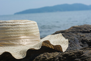 The hat is placed on the rocks by the sea in the sun.