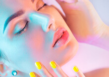 High Fashion Model Girl In Colorful Bright UV Lights Posing In Studio, Portrait Of Beautiful Woman With Trendy Make-up And Manicure. Art Design, Colorful Make Up. Over Colourful Background