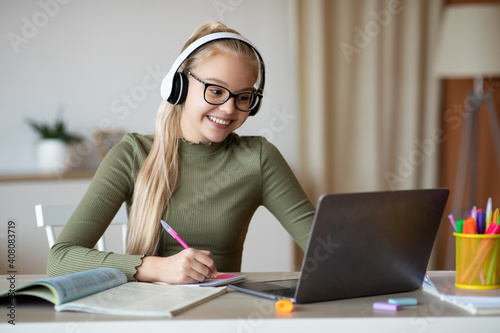 Positive school girl studying from home in front of laptop © Prostock-studio