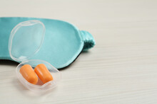 Pair Of Ear Plugs And Sleeping Mask On White Wooden Background. Space For Text