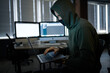 Male hacker in hood holds laptop, front view