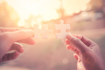Poster - Close Up hand of man and woman connecting jigsaw puzzle with sunlight affect, Business solutions partnership success and strategy concept
