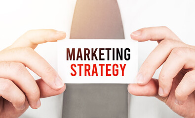 Poster - Businessman holding a card with text Marketing Strategy,business concept
