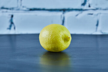 Whole juicy yellow lemon on blue background