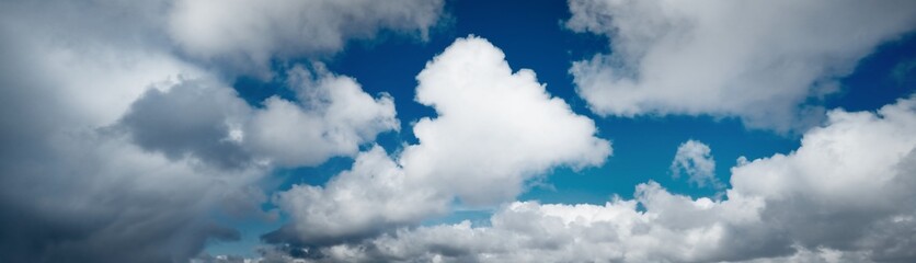 clear blue sky with glowing white cumulus clouds. midday sun. panoramic dramatic cloudscape. concept