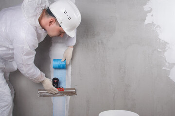 the master applies a reinforced tape with a spatula to strengthen the plastered crack