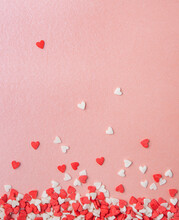 Confetti In The Form Of Red And Pink Hearts Are Scattered On A Pink Shiny Background. Concept Of Valentine's Day, Mother's Day, Wedding Day