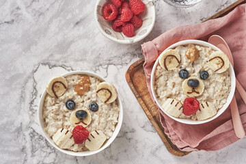 Oatmeal porridge bear with banana and berries, fun food art idea for kids food top view