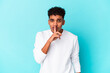 © Asier - Young african american curly man isolated on blue keeping a secret or asking for silence.